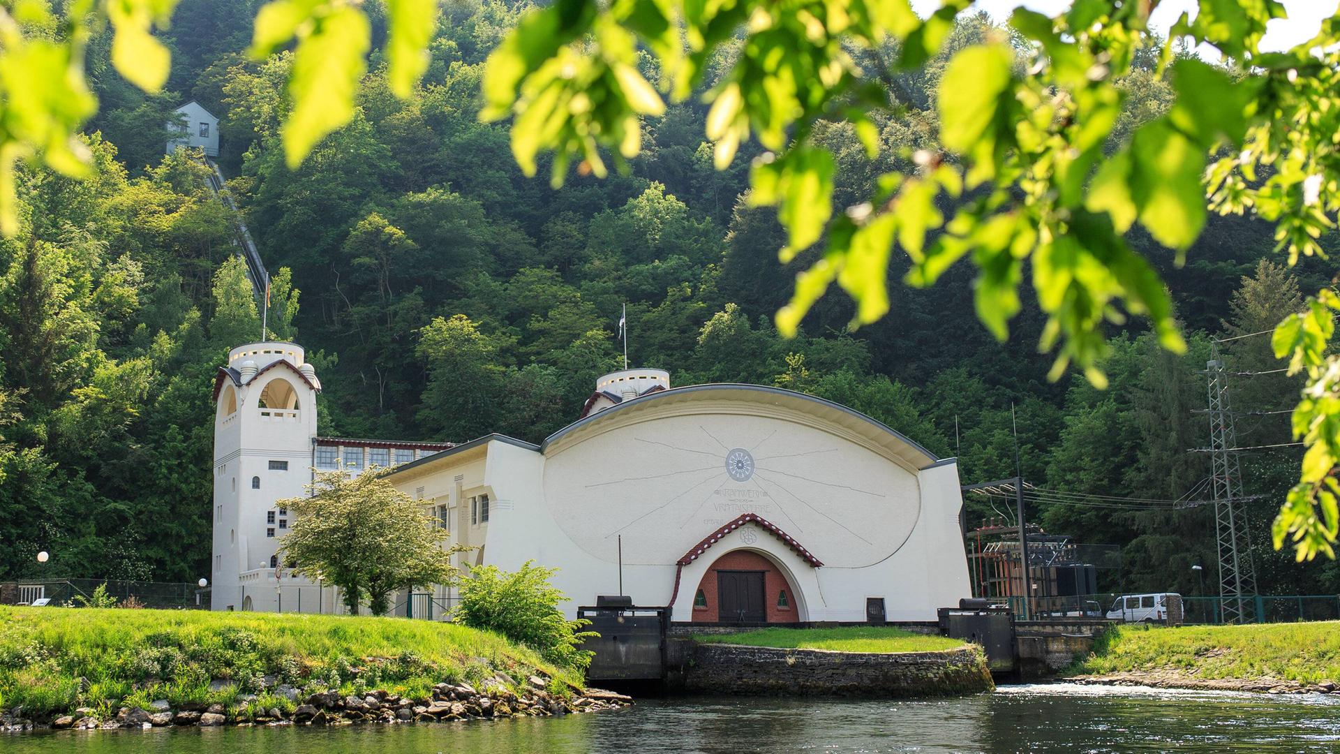 Das weiße, historische Gebäude, das einer Kirche mit Turm gleicht, spiegelt sich im Flusswasser. Das weiße, historische Gebäude, das einer Kirche mit Turm gleicht, spiegelt sich im Flusswasser.