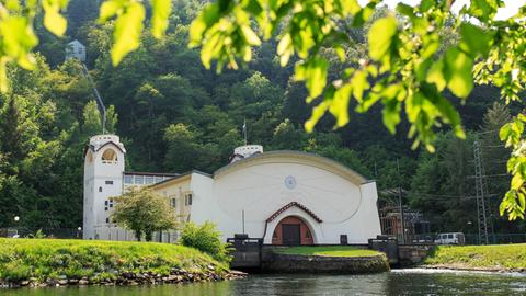 Das weiße, historische Gebäude, das einer Kirche mit Turm gleicht, spiegelt sich im Flusswasser.