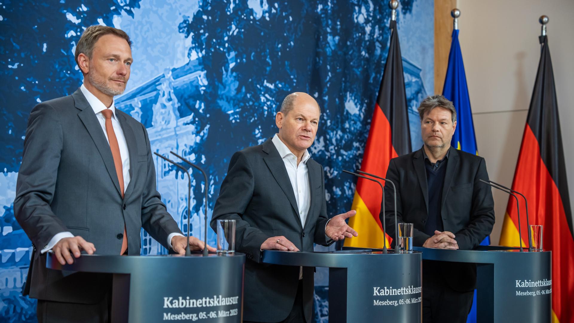 Lindner, Scholz und Habeck stehen an drei Redepulten. Im Hintergrund sieht man zwei Deutschland-Fahnen und die Flagge der Europäischen Union. Lindner, Scholz und Habeck stehen an drei Redepulten. Im Hintergrund sieht man zwei Deutschland-Fahnen und die Flagge der Europäischen Union.