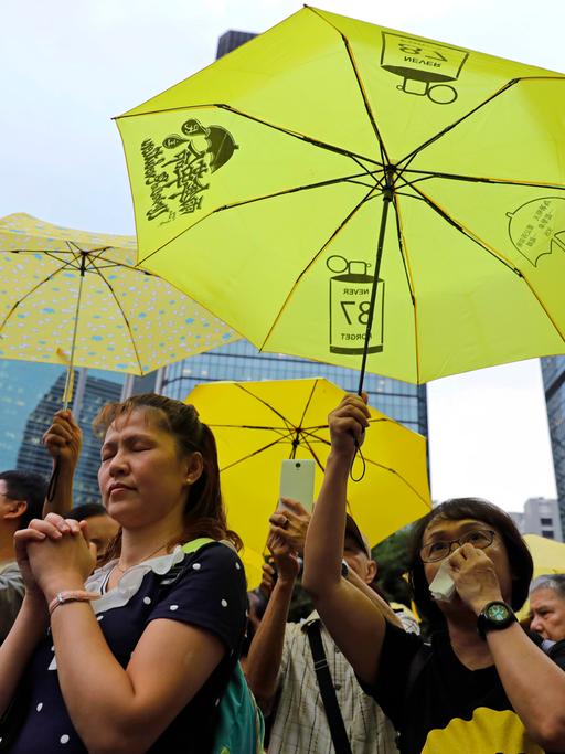Demonstrierende in Hongkong. Sie tragen  gelbe Schirme.