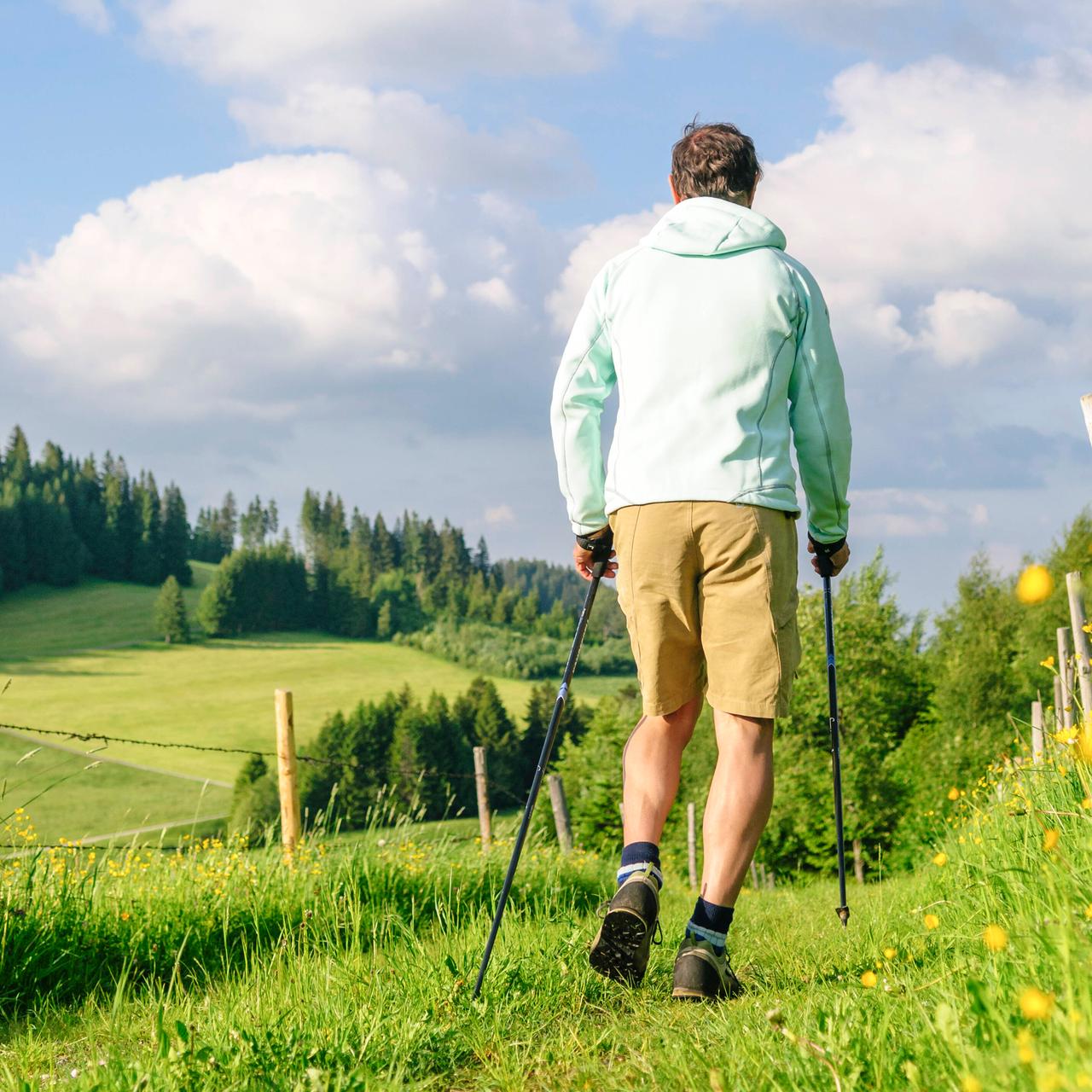 Eine Person walkt mit Stöcken einen Feldweg entlang. Eine Person walkt mit Stöcken einen Feldweg entlang.