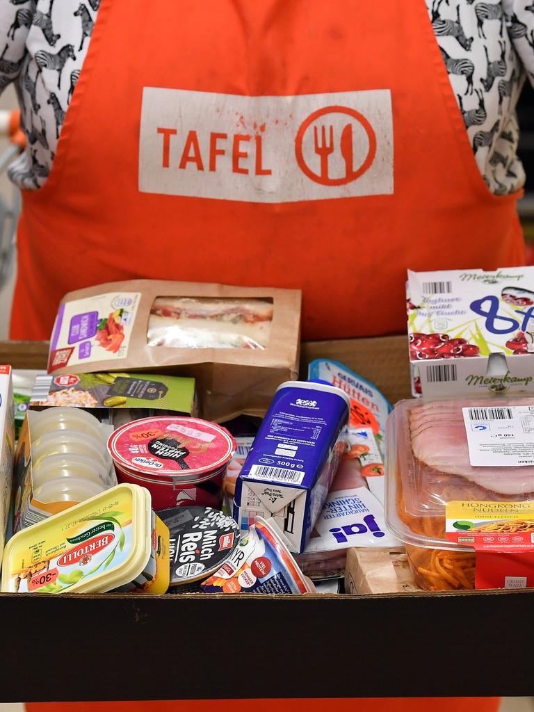 Eine Person mit Tafeln-Schürze und einem Karton voller Lebensmittel