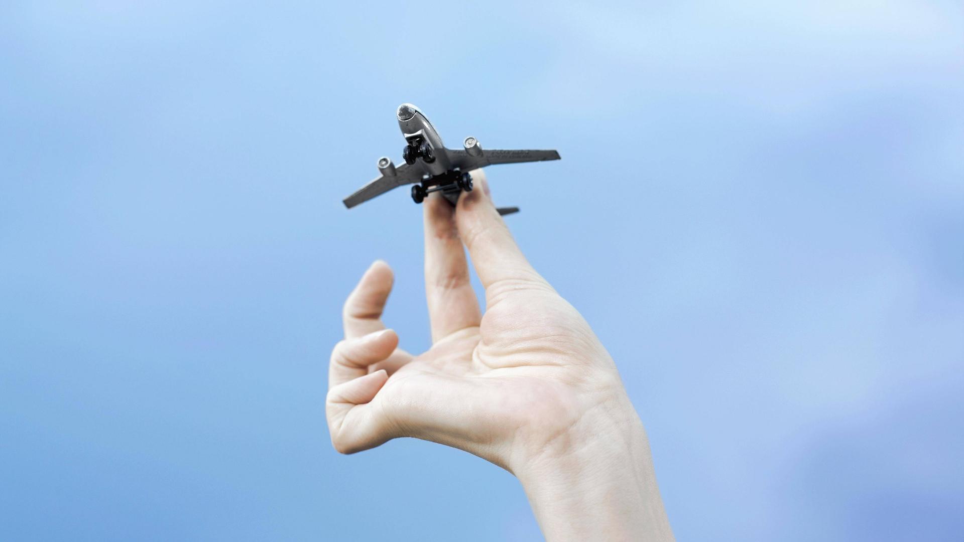 Eine Hand hält ein Modellflugzeug vor blauem Himmel. Eine Hand hält ein Modellflugzeug vor blauem Himmel.