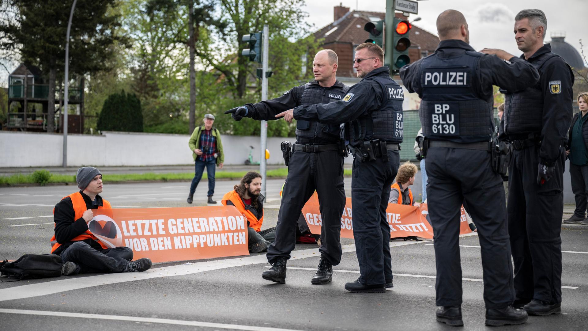 Polizisten besprechen die Vorgehensweise zur Räumung der Kreuzung Hohenzollerndamm/Konstanzer Straße, wo Aktivisten auf der Fahrbahn sitzen.