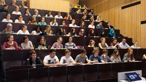 Junge Männer und Frauen in einem Universitätshörsaal. Sie sitzen in mehreren, steil ansteigenden Reihen hintereinander. Es handelt sich um Studierende der Universität Düsseldorf.