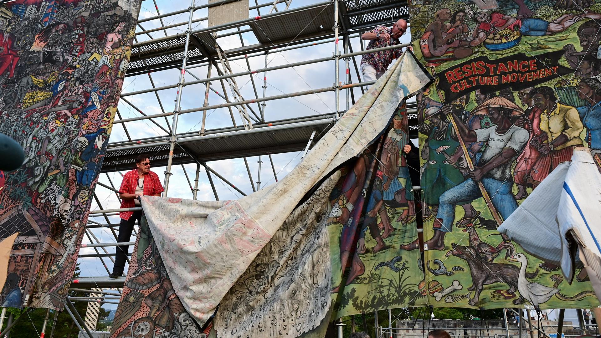 Documenta-Mitarbeiter bauen das umstrittene Großbanner "People's Justice" des indonesischen Künstlerkollektivs Taring Padi auf dem Friedrichsplatz in Kassel ab.