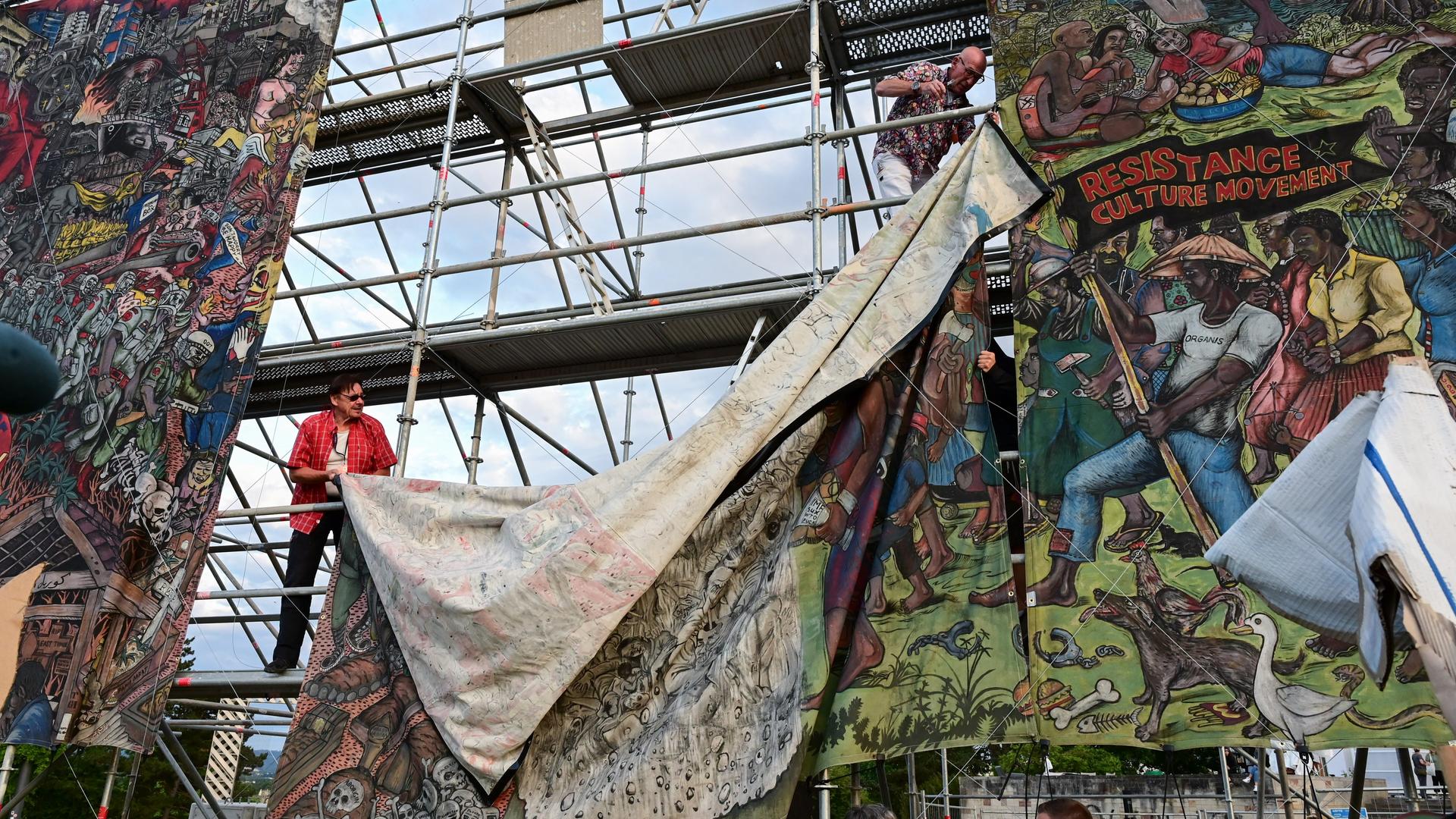 Documenta-Mitarbeiter bauen das umstrittene Banner ab. Documenta-Mitarbeiter bauen das umstrittene Banner ab.