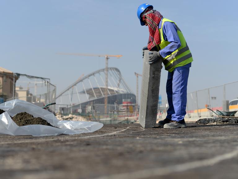 Ein Gastarbeiter bringt an einer Straße vor dem Khalifa-Stadion in der katarischen Hauptstadt Doha einen Bordstein an. 