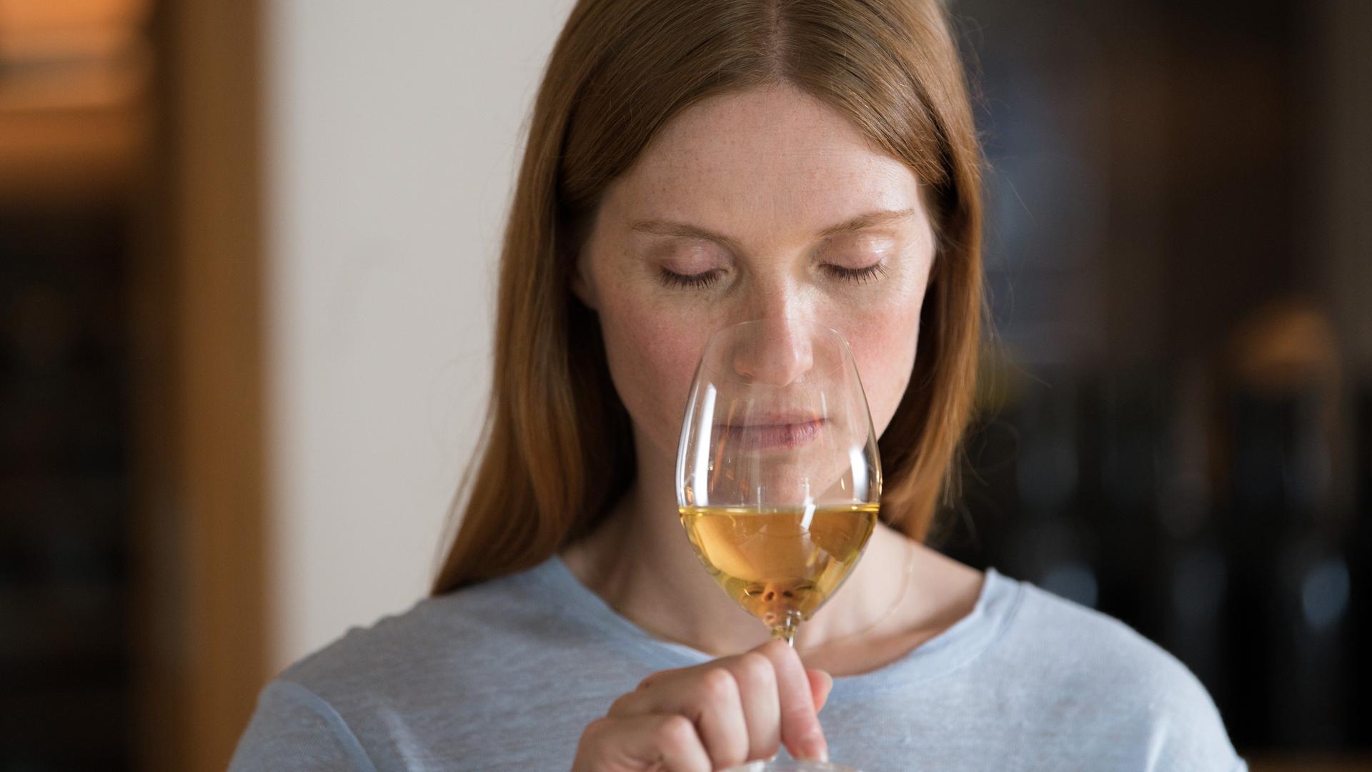Eine Frau riecht mit geschlossenen Augen an einem Glas Weisswein Eine Frau riecht mit geschlossenen Augen an einem Glas Weisswein
