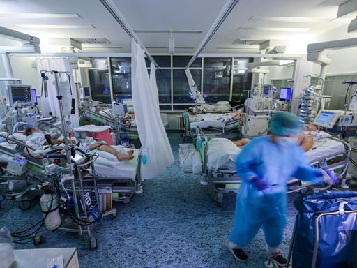 Eine Intensivpflegerin versorgt einen Covid-19-Patienten auf der Intensivstation der Leipziger Uniklinik in einem Zimmer, in dem noch drei weitere Corona-Patienten liegen.
