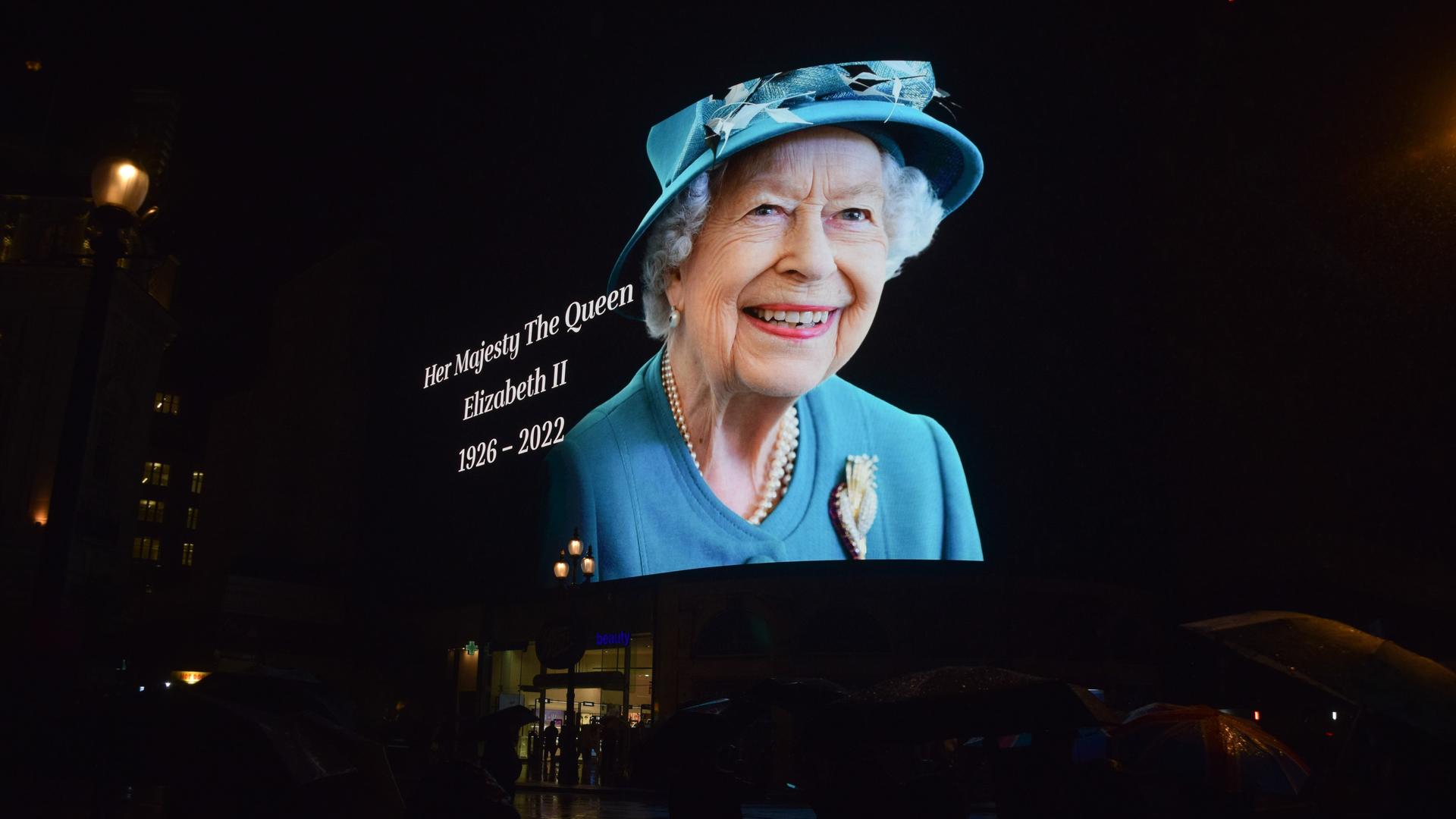 Am 8. September 2022 zeigt eine Reklamewand am Piccadilly Circus das Porträt der Queen, die ein hellblaues Kleid und entsprechenden Hut trägt und freundlich lächelt.