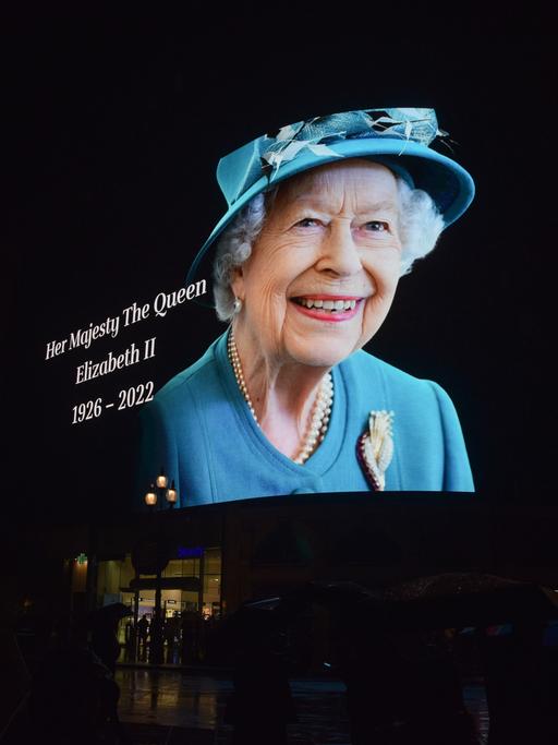 Am 8. September 2022 zeigt eine Reklamewand am Piccadilly Circus das Porträt der Queen, die ein hellblaues Kleid und entsprechenden Hut trägt und freundlich lächelt.