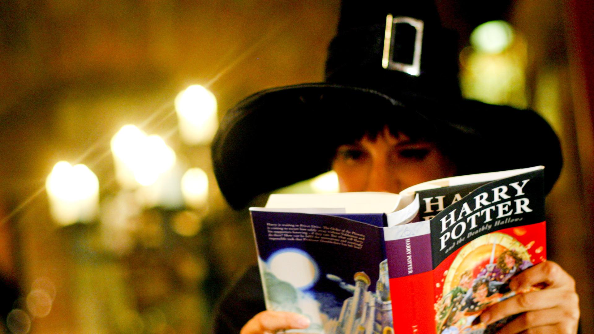 Jemand trägt einen Zauber-Hut und liest ein Harry-Potter-Buch. Jemand trägt einen Zauber-Hut und liest ein Harry-Potter-Buch.