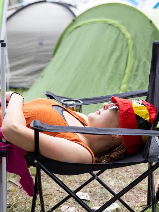 Eine Besucherin beim Open-Air-Festival "Rock im Park" entspannt sich auf einer Liege aus zwei Stühlen gestaltet.