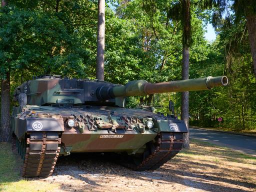 Ein Kampfpanzer des Bundeswehr vom Typ Leopard 2A4 steht in einem Waldstück.