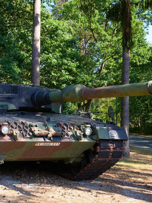 Ein Kampfpanzer des Bundeswehr vom Typ Leopard 2A4 steht in einem Waldstück.