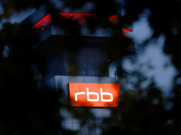 Das beleuchtete Logo des Senders Rundfunk Berlin-Brandenburg (RBB) ist an der Fassade am Sitz des Senders an der Masurenallee in Berlin angebracht.