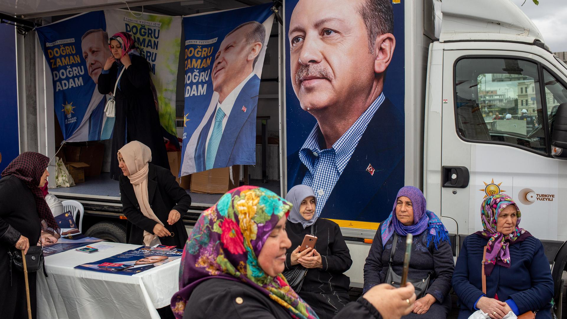 Eine Gruppe von Frauen mit Kopftuch sitzt vor Plakaten, die den türkischen Präsidenten Recep Tayyip Erdoğan zeigen.