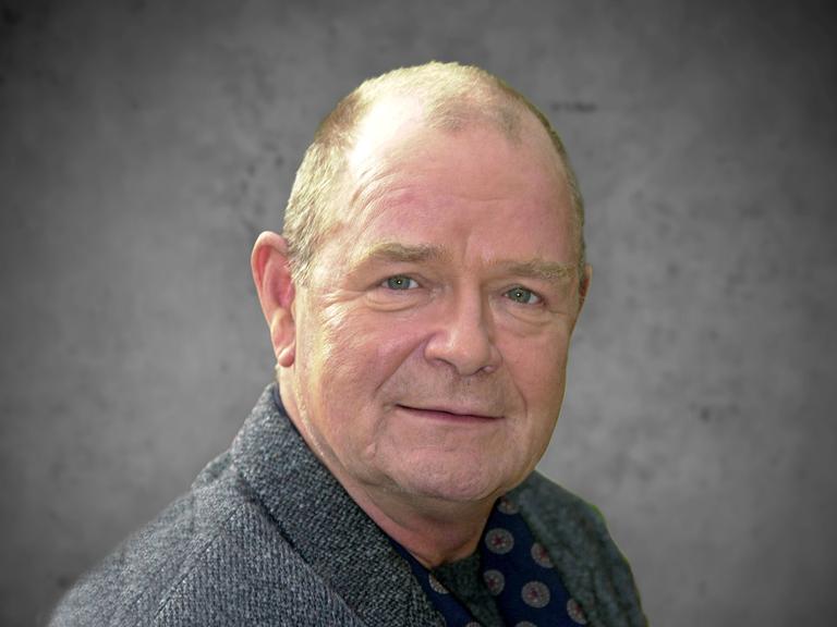 Porträt von Dieter Mann, ein älterer Mann mit Halbglatze und grauem Pullover