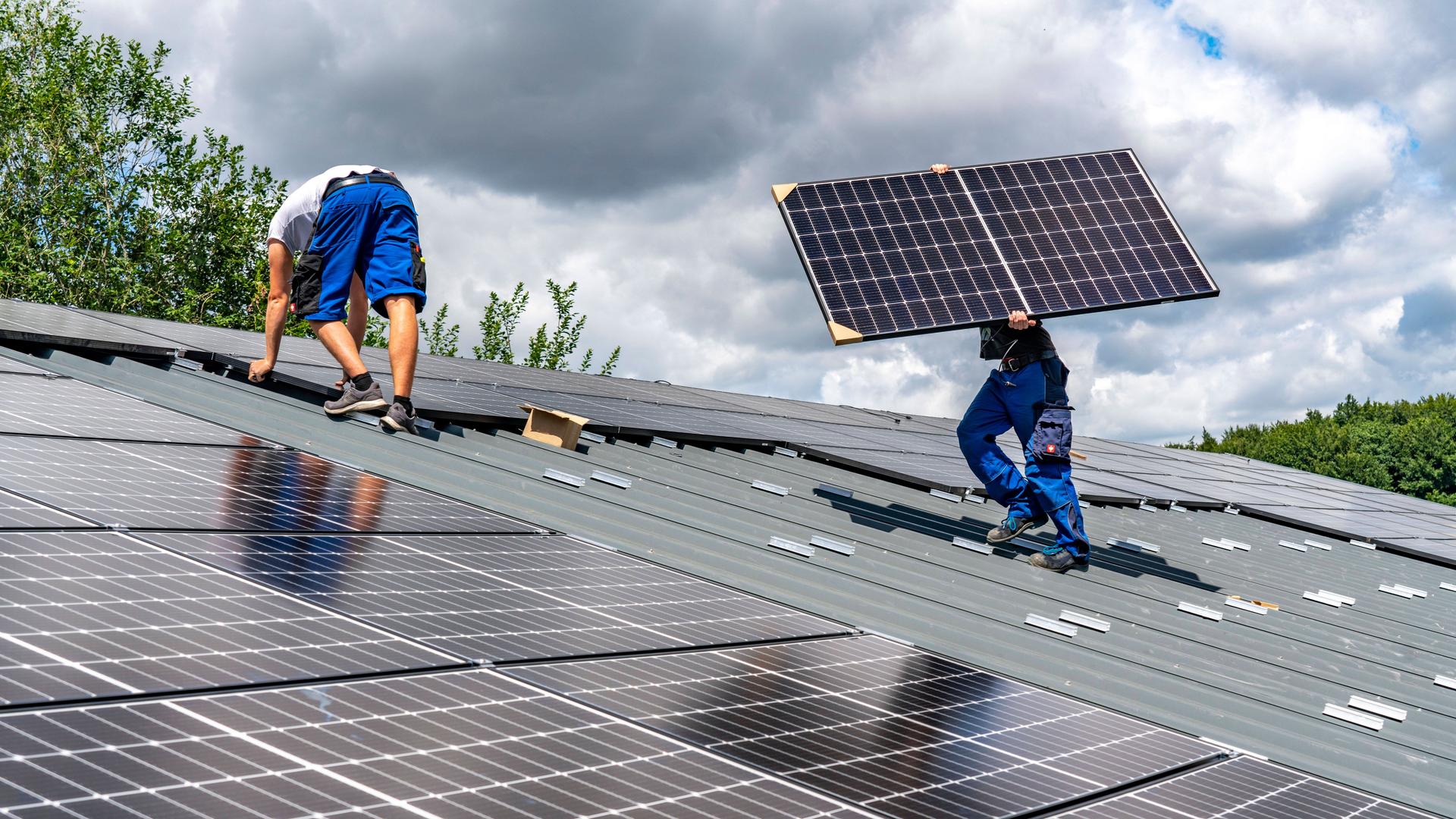 Monteure bauen Solarmodule auf ein Dach. Monteure bauen Solarmodule auf ein Dach.