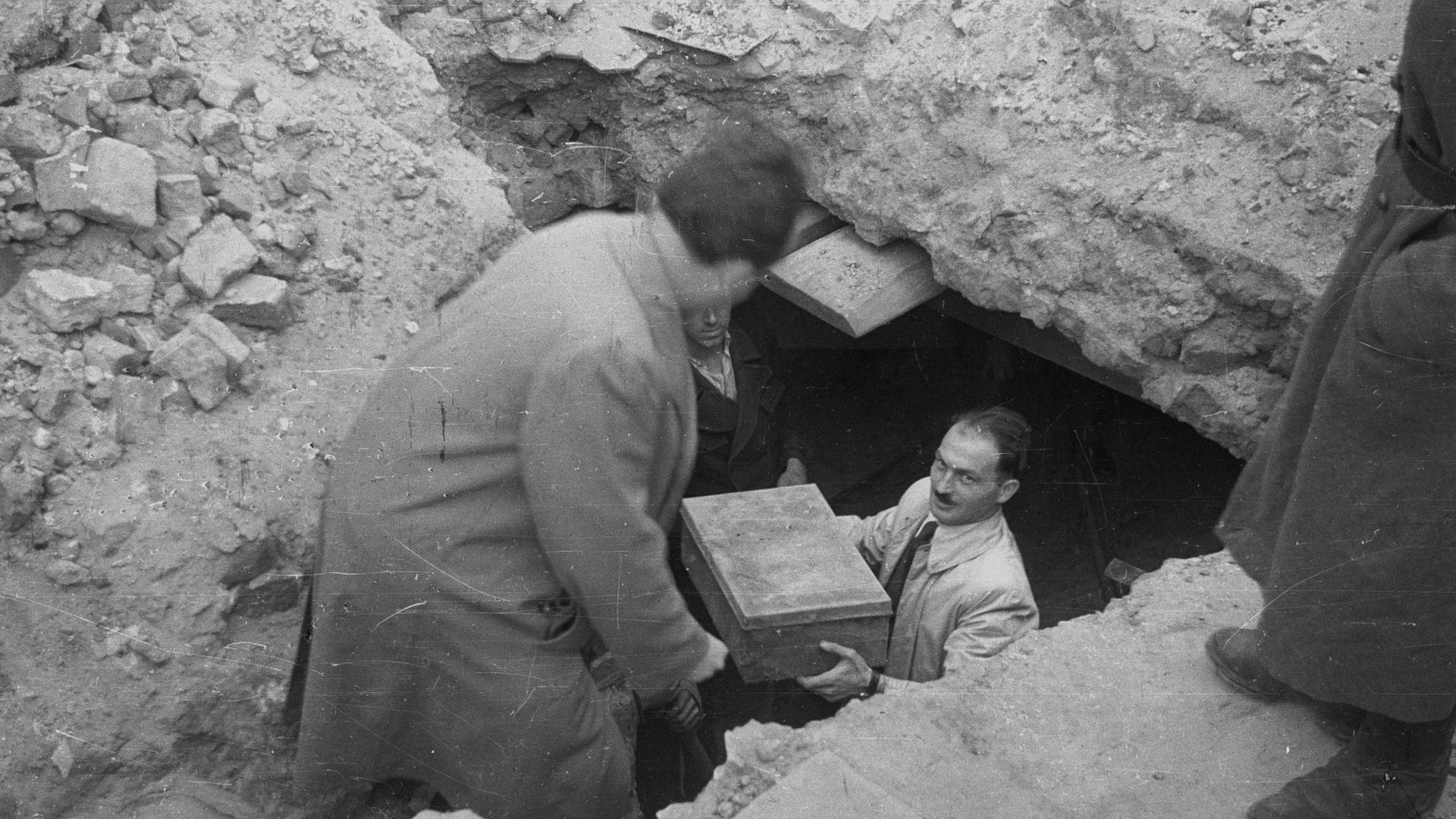 Ein Helfer trägt eine Kiste mit Erinnerungen aus einem Erdlloch unter dem Warschauer Getto. Die Fundstücke bilden den Grundstock für das Ringelblum-Archiv. Ein Helfer trägt eine Kiste mit Erinnerungen aus einem Erdlloch unter dem Warschauer Getto. Die Fundstücke bilden den Grundstock für das Ringelblum-Archiv.