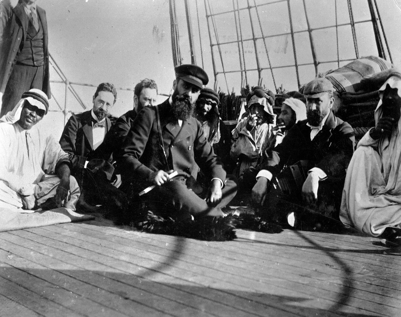 Der ungarisch-jüdische Schriftsteller Theodor Herzl sitzt auf dem Boden eines Bootes und ist umringt von anderen Menschen