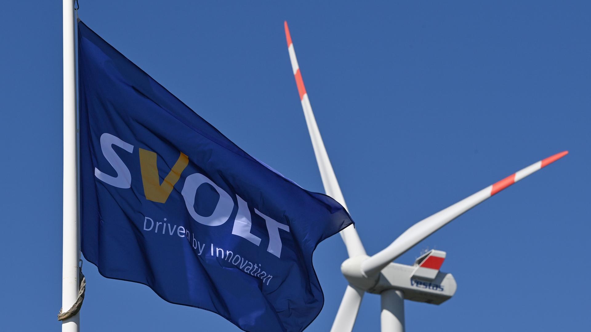 Eine Fahne des Batterieherstellers Svolt weht im Wind vor einer Windenergieanlage