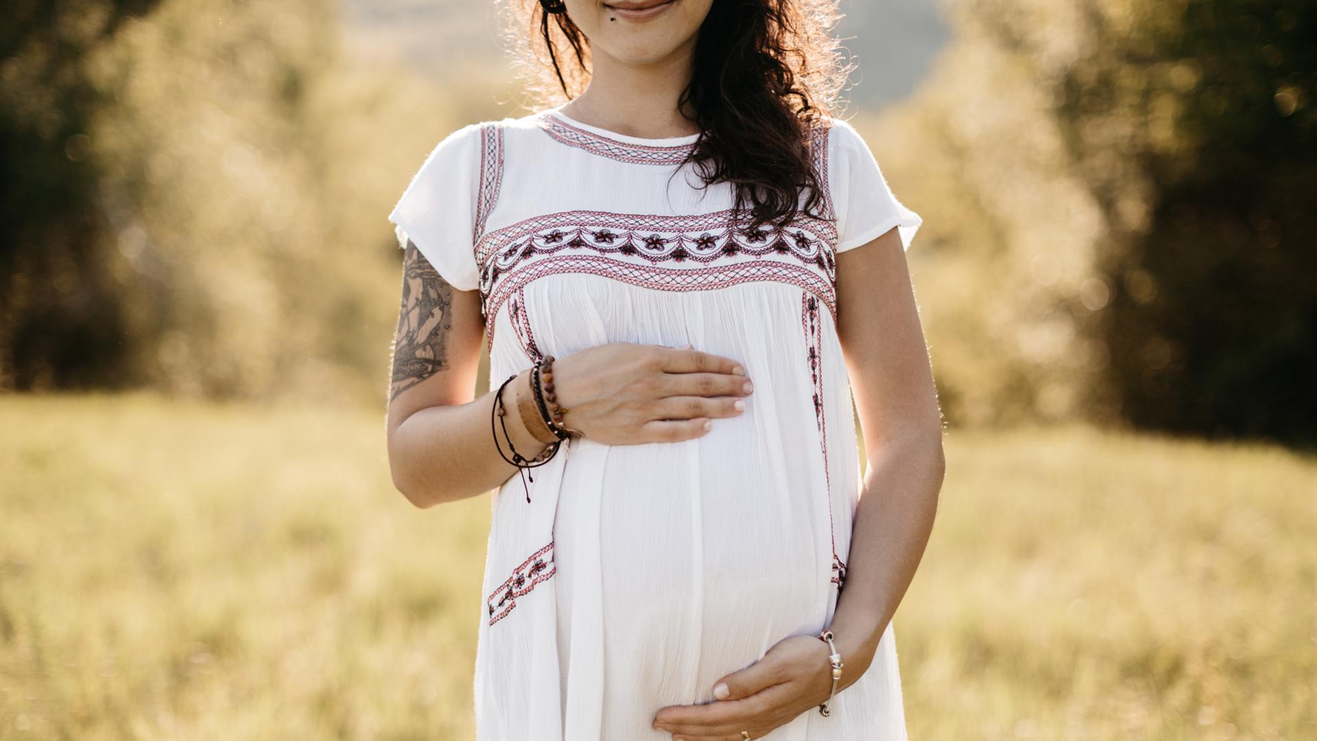 Das Hörspiel basiert auf einer wahren Begebenheit. 2014 wurden sieben Teenager in Bosnien und Herzegowina "kollektiv" schwanger. Zu sehen: Eine junge Frau (Gesicht erst ab den Lippen zu sehen) in einem weißen Kleid hält ihre Hände über den schwangeren Bauch. 