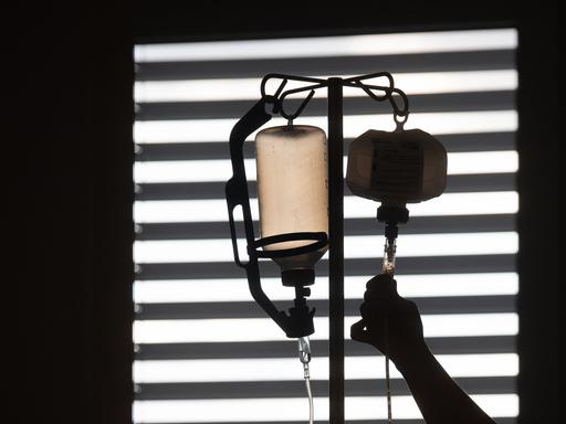 Eine Krankenpflegerin kontrolliert die Infusion eines Patienten.