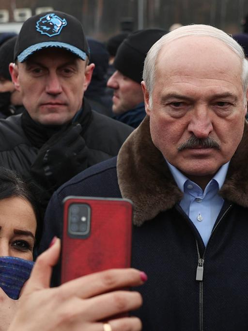 Eine Frau macht mit ihrem Handy ein gemeinsames Foto mit dem belarussischen Präsidenten Alexander Lukaschenko.