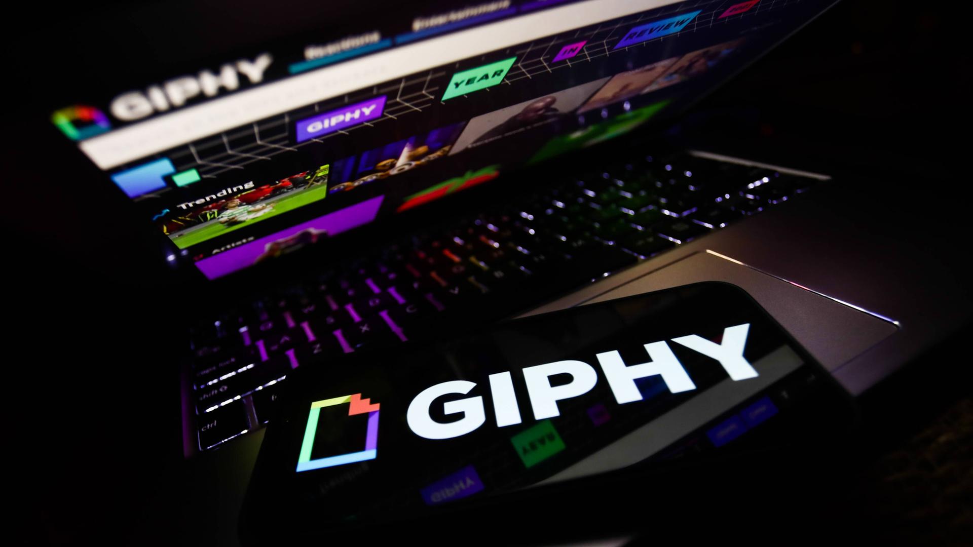 Ein Handy mit dem Giphy-Logo liegt auf einem Laptop, auf dem Giphy aufgerufen ist. Ein Handy mit dem Giphy-Logo liegt auf einem Laptop, auf dem Giphy aufgerufen ist.