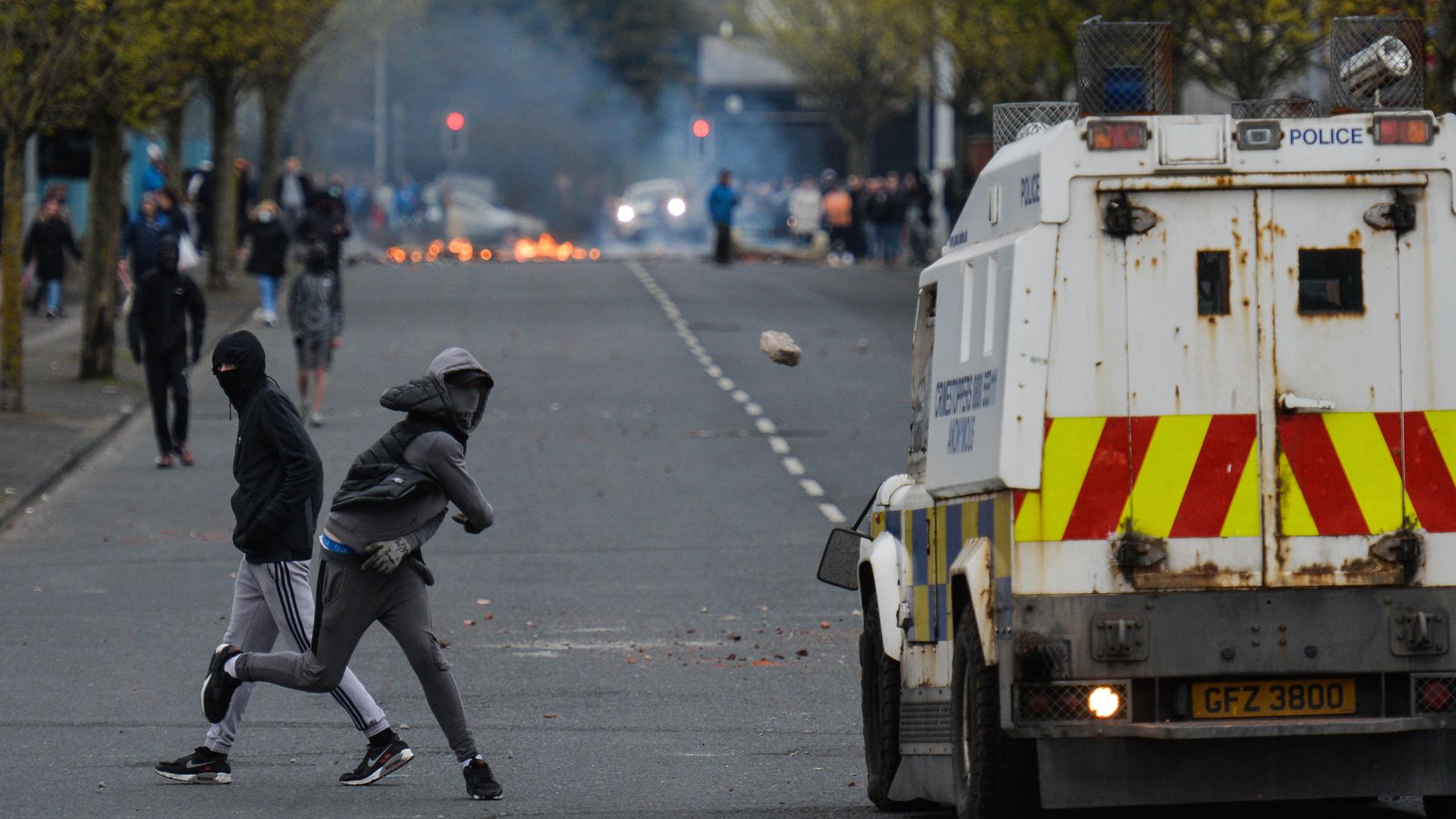 Ein vermummter junger Mann wirft einen Stein auf ein Polizeiauto bei Protesten im April 2021 in Belfast. Ein vermummter junger Mann wirft einen Stein auf ein Polizeiauto bei Protesten im April 2021 in Belfast.