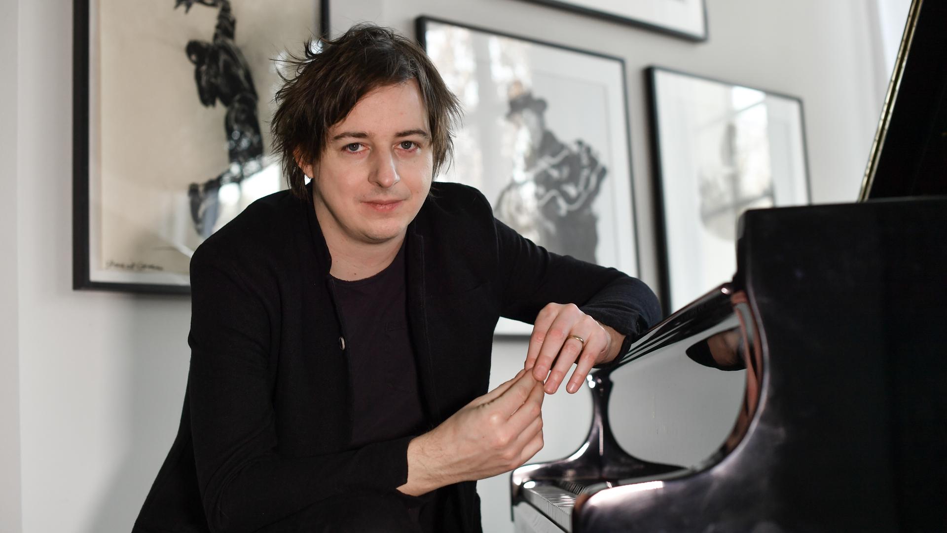 Michael Wollny sitzt an einem Klavier und schaut freundlich in die Kamera. Michael Wollny sitzt an einem Klavier und schaut freundlich in die Kamera.