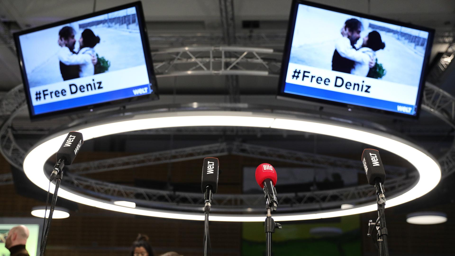 16.02.2018, Berlin: Mikrofone stehen vor der Pressekonferenz anlässlich Freilassung des «Welt»-Korrespondenten Deniz Yücel im Newsroom der Zeitung "Die Welt" vor Bildschirmen, die ein Foto nach seiner Freilassung zeigen. Nach mehr als einem Jahr in türkischer Haft hat der «Welt»-Korrespondent Deniz Yücel das Gefängnis in Silivri bei Istanbul verlassen. (zu "Nach mehr als einem Jahr in türkischer Haft hat der «Welt»-Korrespondent Deniz Yücel das Gefängnis in Silivri bei Istanbul verlassen" vom 16.02.2018) Foto: Kay Nietfeld/dpa +++ dpa-Bildfunk +++ 16.02.2018, Berlin: Mikrofone stehen vor der Pressekonferenz anlässlich Freilassung des «Welt»-Korrespondenten Deniz Yücel im Newsroom der Zeitung "Die Welt" vor Bildschirmen, die ein Foto nach seiner Freilassung zeigen. Nach mehr als einem Jahr in türkischer Haft hat der «Welt»-Korrespondent Deniz Yücel das Gefängnis in Silivri bei Istanbul verlassen. (zu "Nach mehr als einem Jahr in türkischer Haft hat der «Welt»-Korrespondent Deniz Yücel das Gefängnis in Silivri bei Istanbul verlassen" vom 16.02.2018) Foto: Kay Nietfeld/dpa +++ dpa-Bildfunk +++