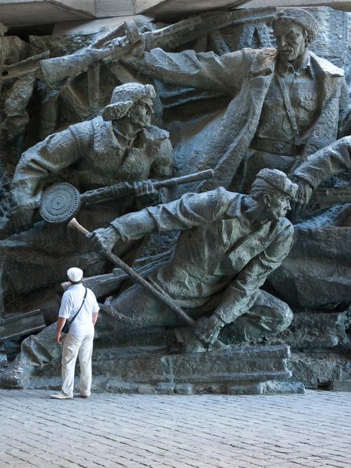 Ein Mann steht vor einer Wandskulptur des Nationalmuseums in Kiew, das den Krieg gegen Hitlerdeutschland darstellt.