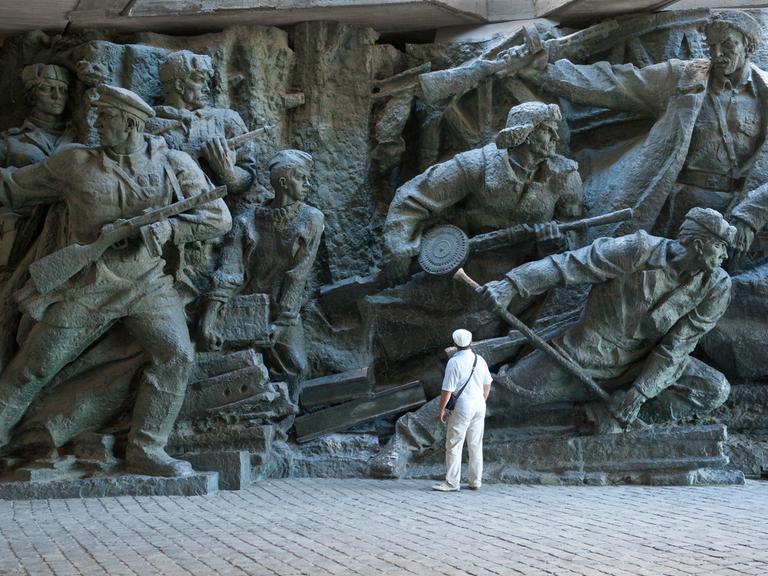 Ein Mann steht vor einer Wandskulptur des Nationalmuseums in Kiew, das den Krieg gegen Hitlerdeutschland darstellt.