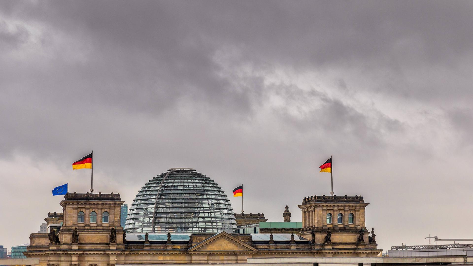 Dunkle Wolken über der gläsernen Kuppel des Reichstagsgebäudes in Berlin Dunkle Wolken über der gläsernen Kuppel des Reichstagsgebäudes in Berlin