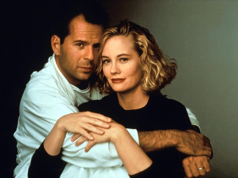 Bruce Willis hält Cybill Shepherd liebevoll umschlungen, sie legt ihre Hände auf seinen Arm.