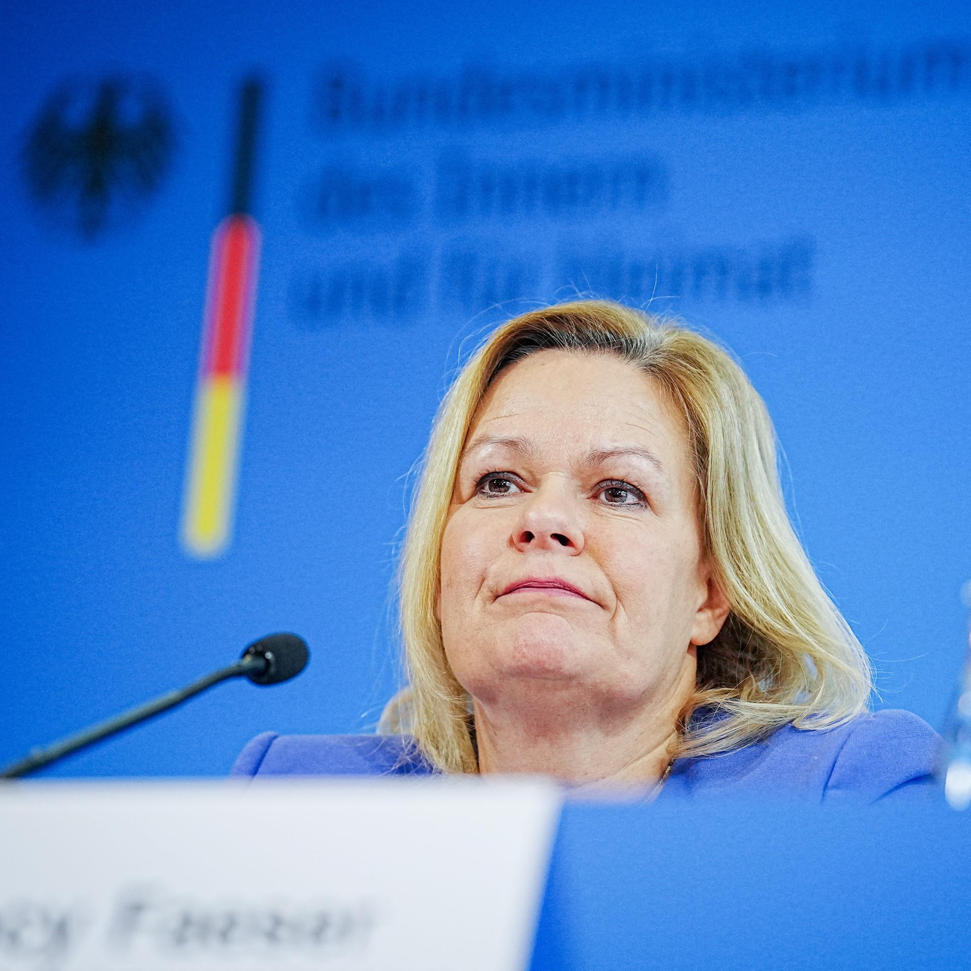 bundesinnenministerin-faeser-sitzt-vor-einem-mikrofon-sie-tr-gt-einen
