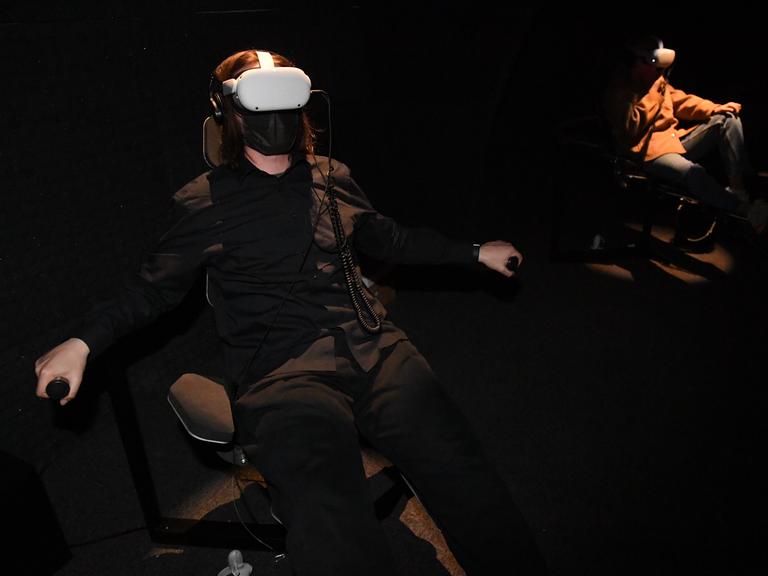 Betrachtende der Arbeit der Künstlerin Loukia Alavanou sitzen im Griechischen Pavillon mit einer Virtual-Reality-Brille auf dem Kopf 2022 auf der 59. Kunstbiennale in Venedig