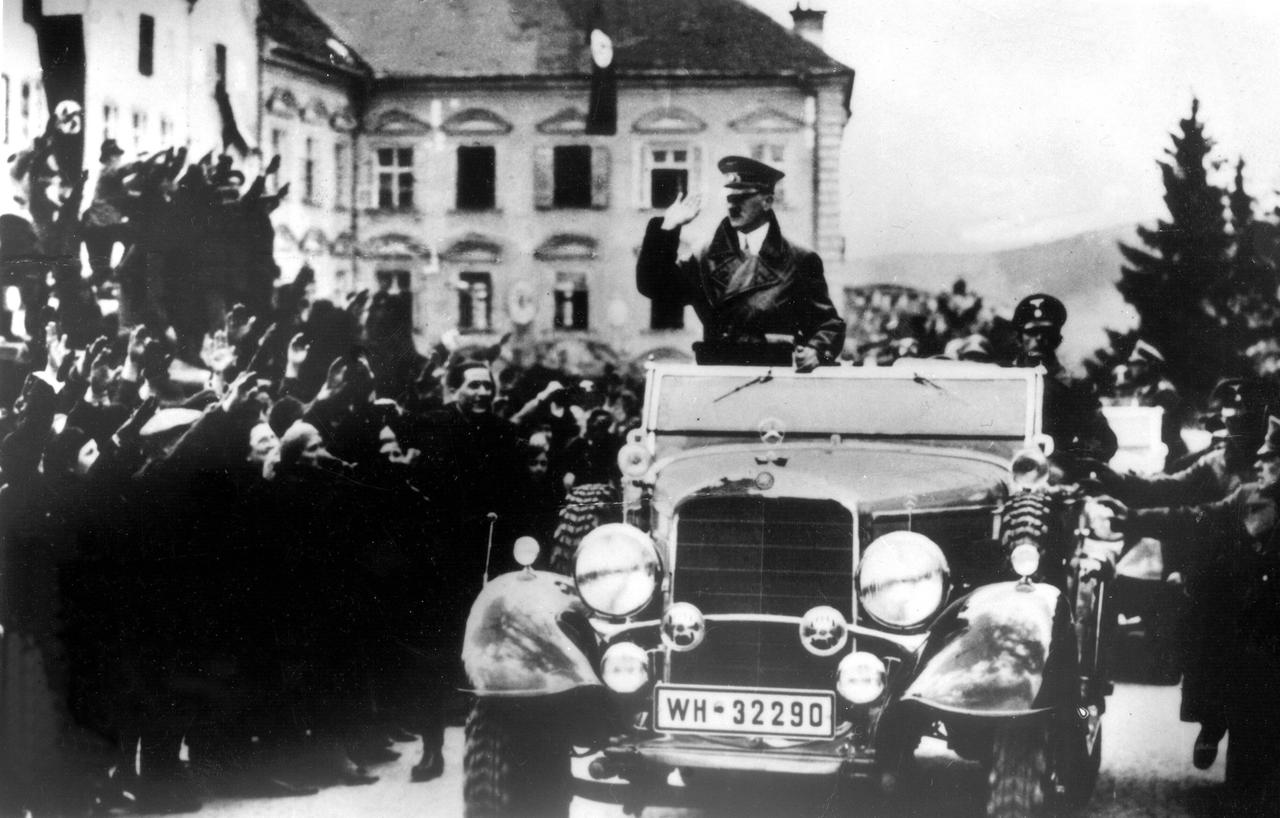 Historische schwarz-weiß-Aufnahme zeigt Adolf Hitler im offenen Fahrzeug bei der Fahrt durch eine Menschenmenge in Linz 1938. Historische schwarz-weiß-Aufnahme zeigt Adolf Hitler im offenen Fahrzeug bei der Fahrt durch eine Menschenmenge in Linz 1938.