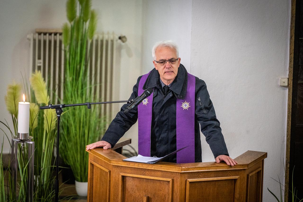 Dietrich Bredt-Dehnen steht mit einer lila Stola um die Schultern auf einer Kanzel und predigt