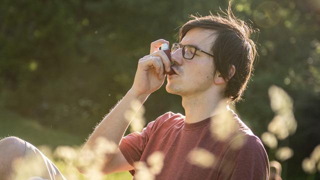 Ein Mann benutzt  in einem Park einen Inhalator