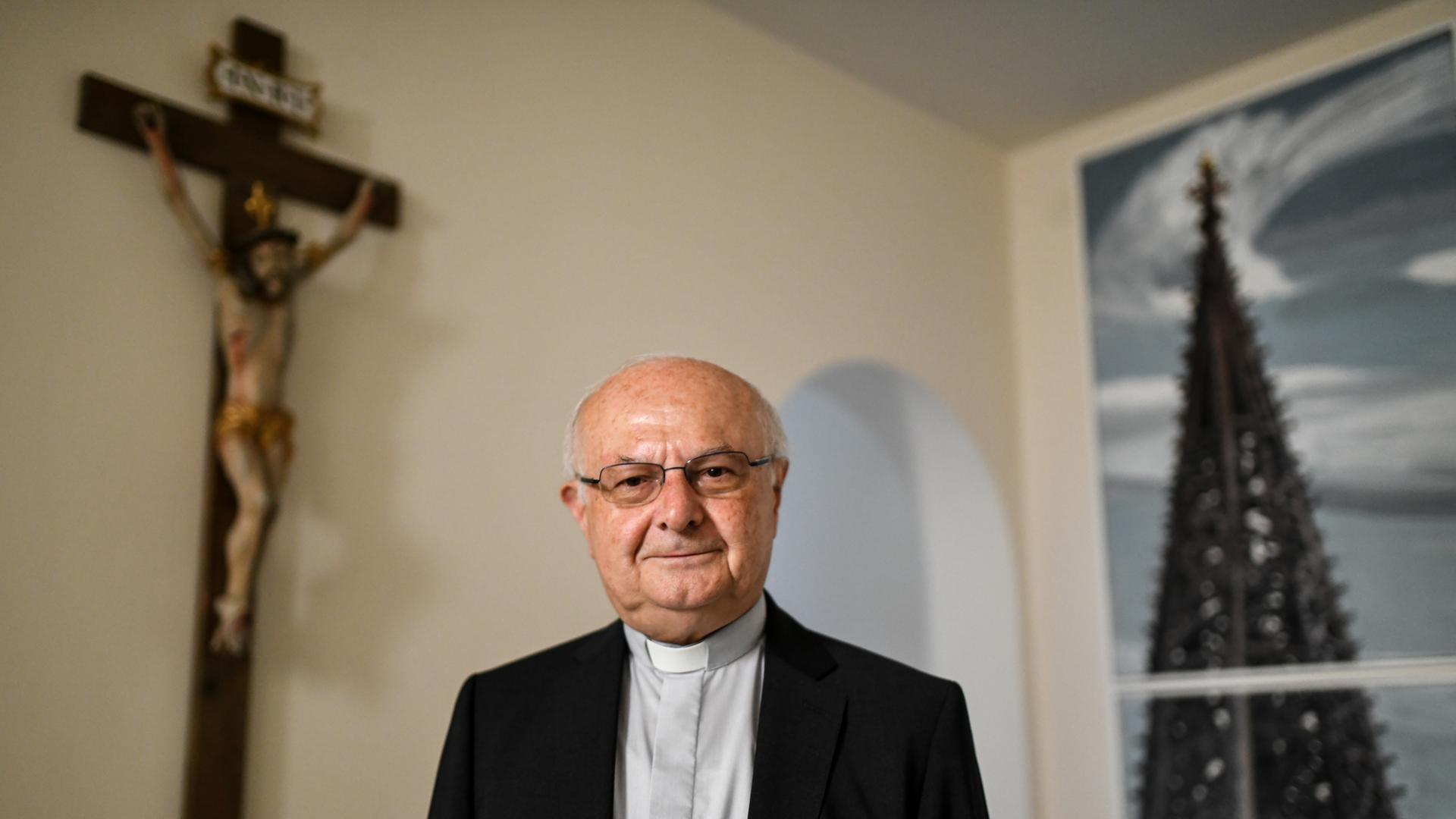 Robert Zollitsch war früher Erzbischof in Freiburg. Er steht in seiner Wohnung vor einem Kreuz.