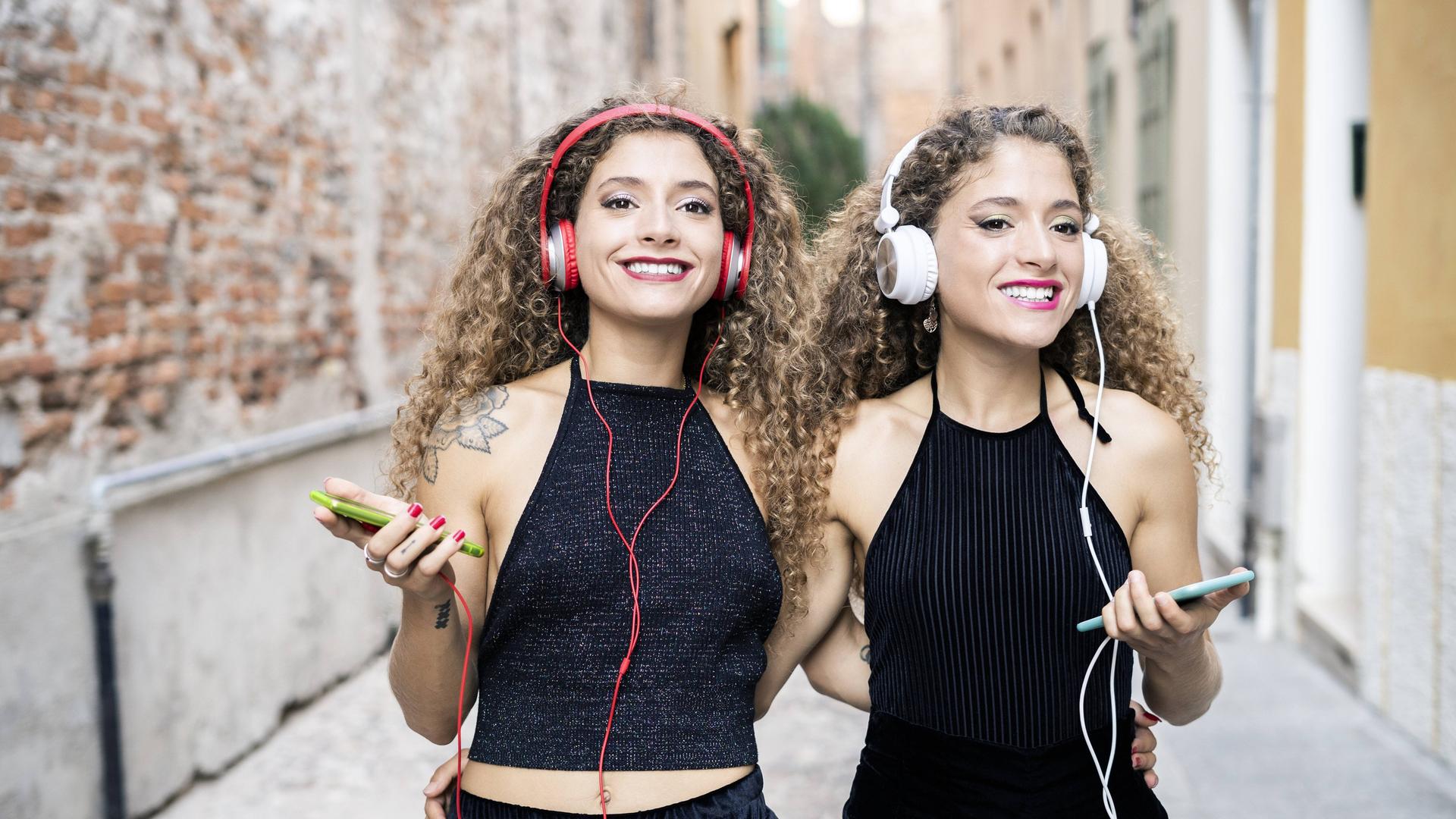 Junge Zwillinge hören Musik mit Handy und Kopfhörer. (Symbolfoto).