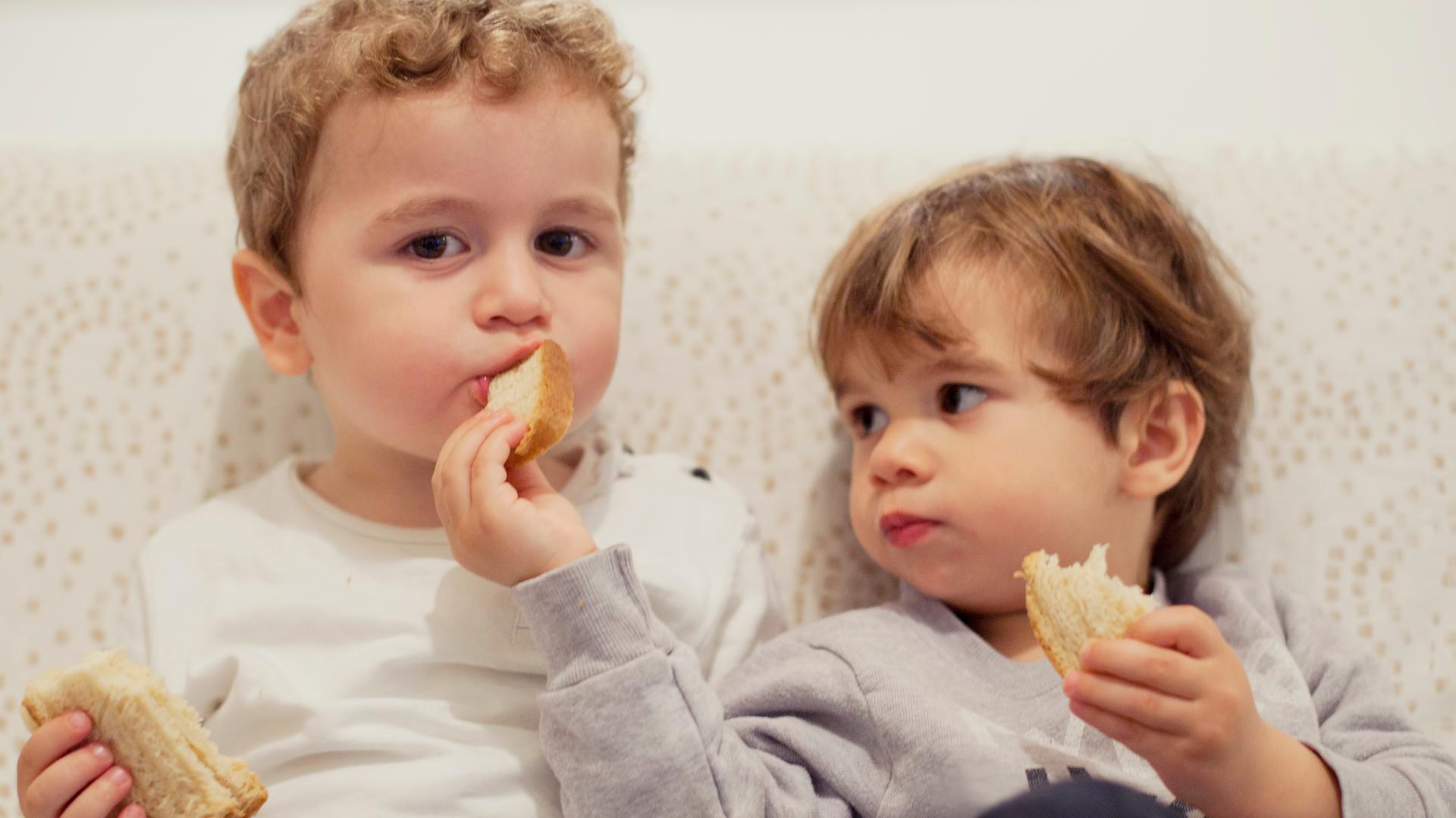Zwei kleine Kinder teilen Brot.