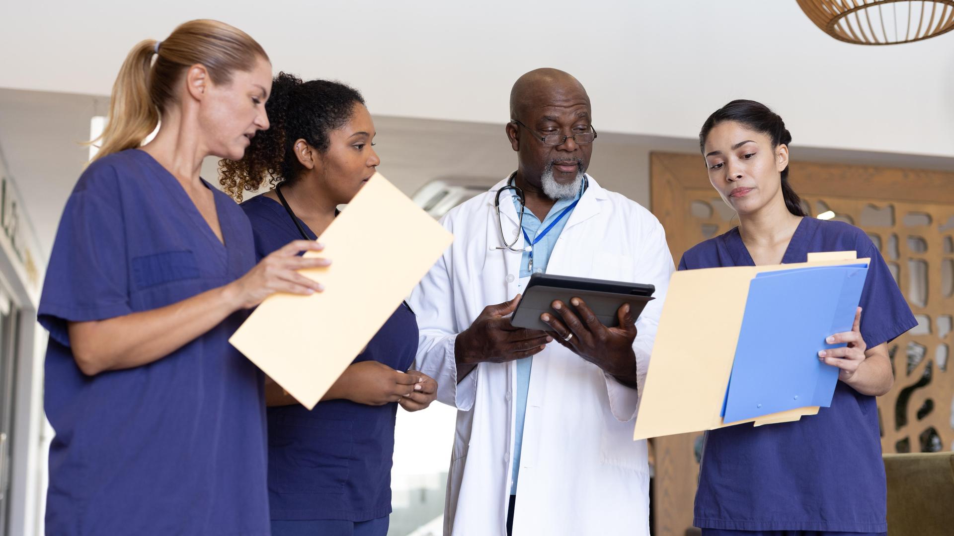 Krankenhausmitarbeiter und -mitarbeiterinnen mit verschiedenen Migrationshintergründen in einer Teambesprechung Krankenhausmitarbeiter und -mitarbeiterinnen mit verschiedenen Migrationshintergründen in einer Teambesprechung