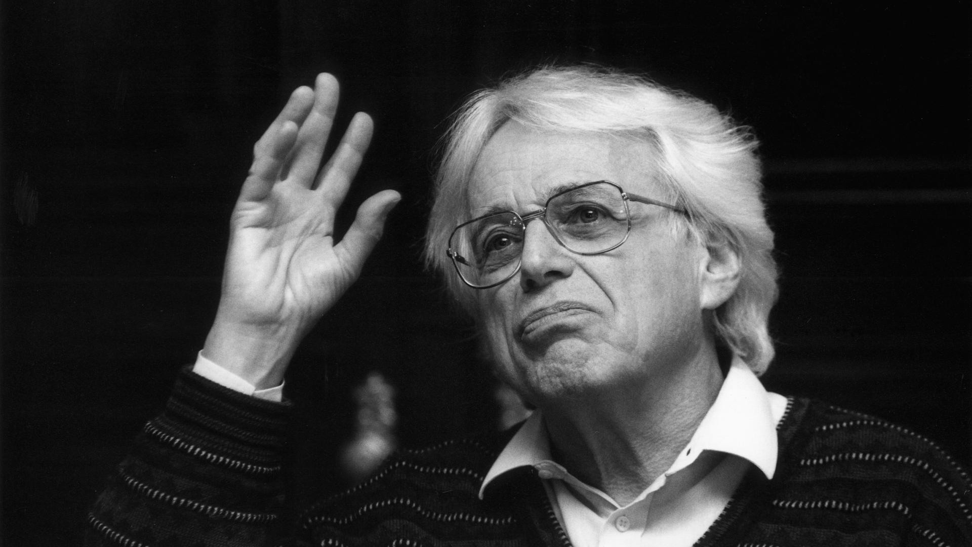Schwarz-weiß-Foto von György Ligeti aus dem Jahr 1992, bei dem er eine Hand hebt und erst an der Kamera vorbei schaut. Schwarz-weiß-Foto von György Ligeti aus dem Jahr 1992, bei dem er eine Hand hebt und erst an der Kamera vorbei schaut.
