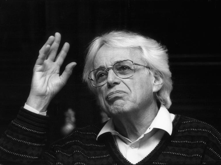 Schwarz-weiß-Foto von György Ligeti aus dem Jahr 1992, bei dem er eine Hand hebt und erst an der Kamera vorbei schaut.