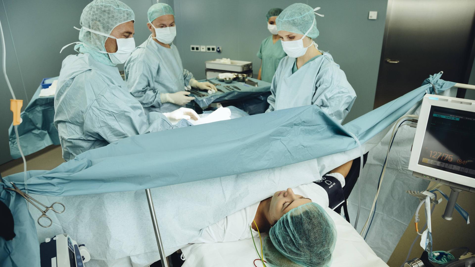 Ein Team operiert eine Frau auf einem Operationstisch. Ein Team operiert eine Frau auf einem Operationstisch.